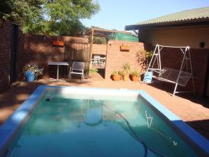 a swimming pool in a backyard with a table and a swing at Kudu Cottages in Kathu