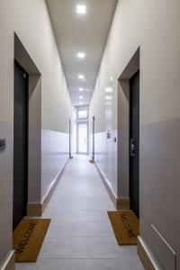 Aparthotel Sant'Orsola في بولونيا: مدخل مبنى بجدران بيضاء وممر طويل