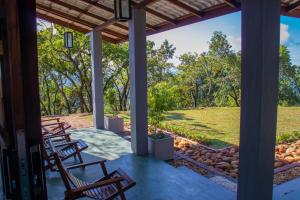 a porch with chairs and a view of a field at Windy Hills Bungalow in Belihul Oya