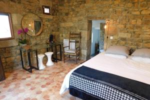 um quarto com uma cama e uma parede de pedra em Chambre d'hôtes les Cerisiers em Vesseaux