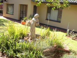 a statue in a garden in front of a house at Kudu Cottages in Kathu