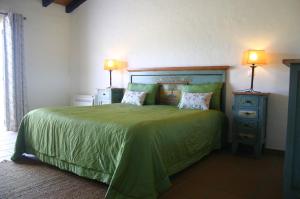 a bedroom with a green bed and two night stands at Monte das Faias Cork Farm Hotel in Grândola +30 photos