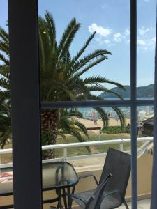 a balcony with a view of a palm tree and the beach at Marinis Boutique Rooms in Iraklitsa