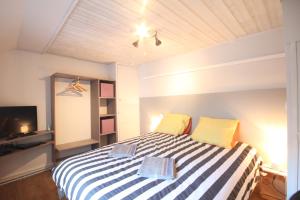 Schlafzimmer mit einem Bett mit gelben und weißen Streifen in der Unterkunft Entre Mer et Golf in Étretat