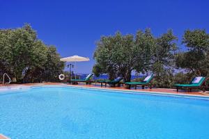 a large swimming pool with chairs and an umbrella at Marilena Sunset Villa 1 in Pomos