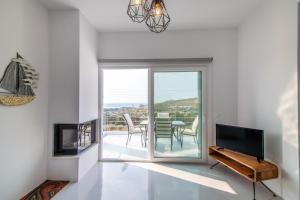 un soggiorno con TV e un balcone con tavolo di Aegean colors Tinos a Città di Tinos