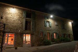 - un bâtiment en pierre la nuit avec un éclairage de rue dans l'établissement Domaine Bellelauze, à Bouriège