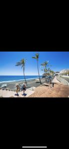 un grupo de personas caminando por una playa con palmeras en Daniela, en Puerto Naos