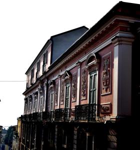 un bâtiment rose avec un balcon dans une rue dans l'établissement La Casa nel Borgo Antico, à Melfi