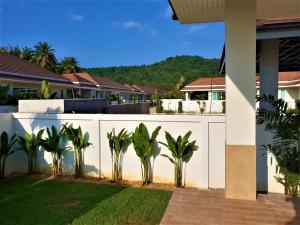 a white fence with palm trees in front of a house at Villa de Veluwe @ Hua Hin in Hua Hin