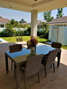 une table avec des chaises et un vase avec des fleurs. dans l'établissement Villa de Veluwe @ Hua Hin, à Hua Hin