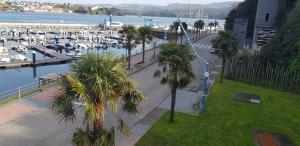 a street with palm trees and a marina with boats at Hostal Ponte Dos Santos in Ribadeo