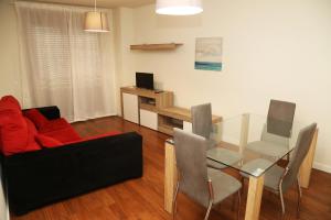 ein Wohnzimmer mit einem roten Sofa und einem Glastisch in der Unterkunft Apartamentos Turísticos Puente Romano P2 2-A in Salamanca