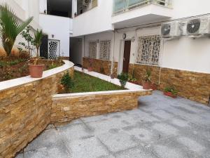 a courtyard of a house with a stone wall at Appartement Djenane El Malik Hydra in Alger