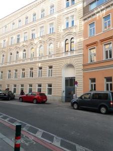 ウィーンにあるThe White Apartmentの大きな建物の前に駐車した車両2台