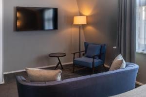 - un salon avec un canapé, une chaise et une télévision dans l'établissement The Resident Covent Garden, à Londres
