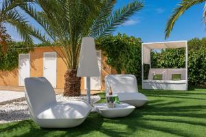 dos sillas blancas sentadas en el césped con un espejo en Serena Villa en Ibiza