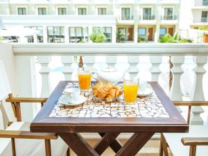 a table with two glasses of orange juice and croissants on a balcony at Casa Di Mare in Olympic Beach