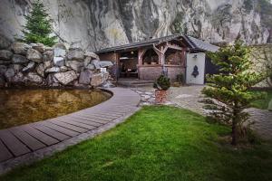 a house with a pond in front of a rock wall at Kúria Beckov - Penzión in Beckov