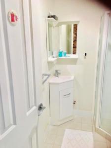 uma casa de banho branca com um lavatório e um espelho em Gorgeous studio 2 minutes from the heart of Subiaco em Perth