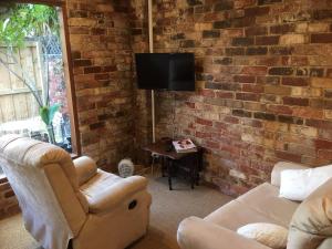 a living room with a couch and a chair and a tv at Gorgeous studio 2 minutes from the heart of Subiaco in Perth