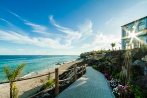a walkway to a beach with a house and the ocean at Royal Palm Resort & Spa - Adults Only in Playa Jandia