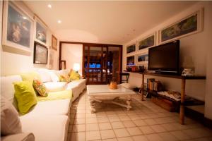 a living room with a white couch and a tv at Pousada Casa do Bicho Preguiça in Angra dos Reis
