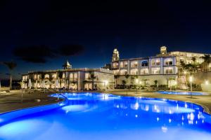 a large blue pool in front of a building at night at Royal Palm Resort & Spa - Adults Only in Playa Jandia
