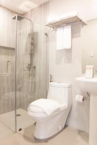 a white bathroom with a toilet and a shower at Hotel Rosita in Lucena