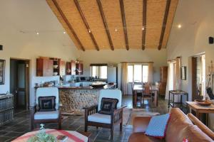 a living room with a couch and chairs and a kitchen at Ribboksfontein Guest Farm in De Rust