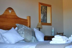 a bedroom with a bed with white pillows and a mirror at Ribboksfontein Guest Farm in De Rust