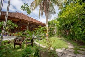 a garden in front of a house with palm trees at Nushe Hostel & Room in Nusa Penida