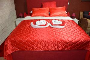 a red bed with two pairs of slippers on it at Sobe apartmani Zagreb SAZ in Zagreb