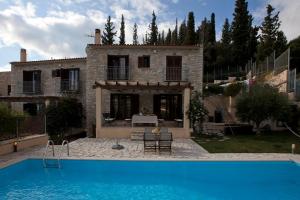 a villa with a swimming pool in front of a house at Parathalasso Villas in Monastiraki