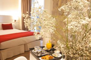 una habitación de hotel con una cama y una mesa con flores en Hotel Pompaelo Plaza del Ayuntamiento & Spa, en Pamplona