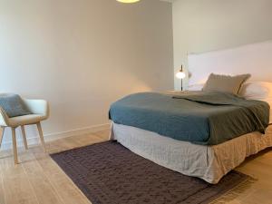 a bedroom with a large bed and a chair at La Maison de l’Ocean - plage à 75 mètres in Saint-Martin-de-Ré