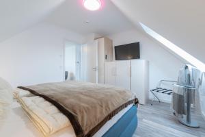 a white bedroom with a bed and a tv at Haus Strandperle in Börgerende-Rethwisch