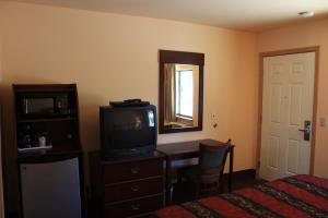 1 dormitorio con TV, escritorio y cama en Gold Trail Motor Lodge, en Placerville