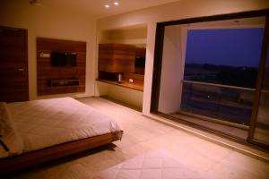 een slaapkamer met een bed en een groot raam bij The Bliss Hotel in Somnath