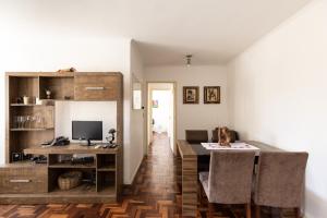 ein Wohnzimmer mit einem Tisch und einem Schreibtisch mit einem Computer in der Unterkunft Apartamento Jardim Botânico 3 quartos 3 vagas para carro in Porto Alegre