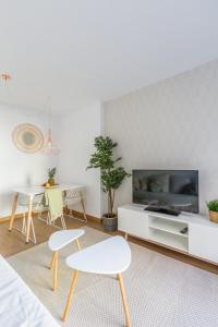 uma sala de estar com duas cadeiras brancas e uma televisão em Horoko Apartments by gaiarooms em Madrid