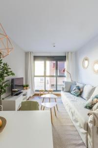 a living room with a white couch and a table at Horoko Apartments by gaiarooms in Madrid