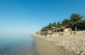 uma praia com uma fila de cadeiras e o oceano em Gerakina beach cottage em Psakoudia