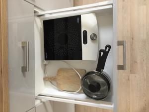 einen weißen Schrank mit einer Mikrowelle und Küchenutensilien. in der Unterkunft SATYS Apartments in Ostrava
