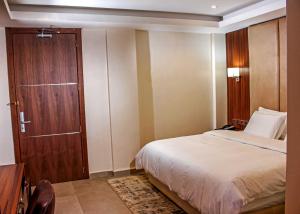 1 dormitorio con 1 cama y puerta de madera en Joshesther Olive Hotel, en Ikeja