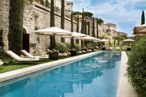 a patio with a pool, chairs, and tables at Airelles Gordes, La Bastide in Gordes