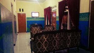a room with two chairs and a tv in it at Nakula's Guest House in Banyuwangi