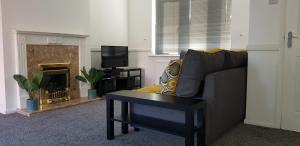 sala de estar con sofá, mesa y chimenea en Maplewell House en Leicester
