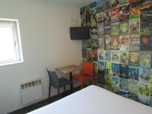 een kamer met een tafel en twee stoelen en een muur met posters bij hotelF1 Igny Massy TGV in Igny