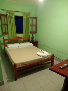 a bedroom with a wooden bed with green curtains at Hostal Portal del Valle in Cafayate